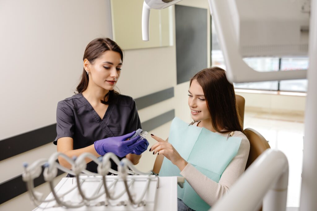 Dentist holding transparent aligners for teeth correction for a patient in dentistry clinic