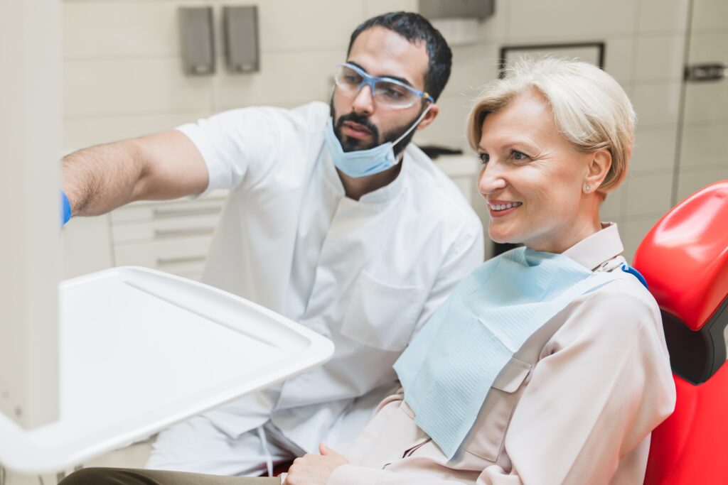 Dentist orthodontist showing explaining an x-ray photo of jaws on computer screen to patient