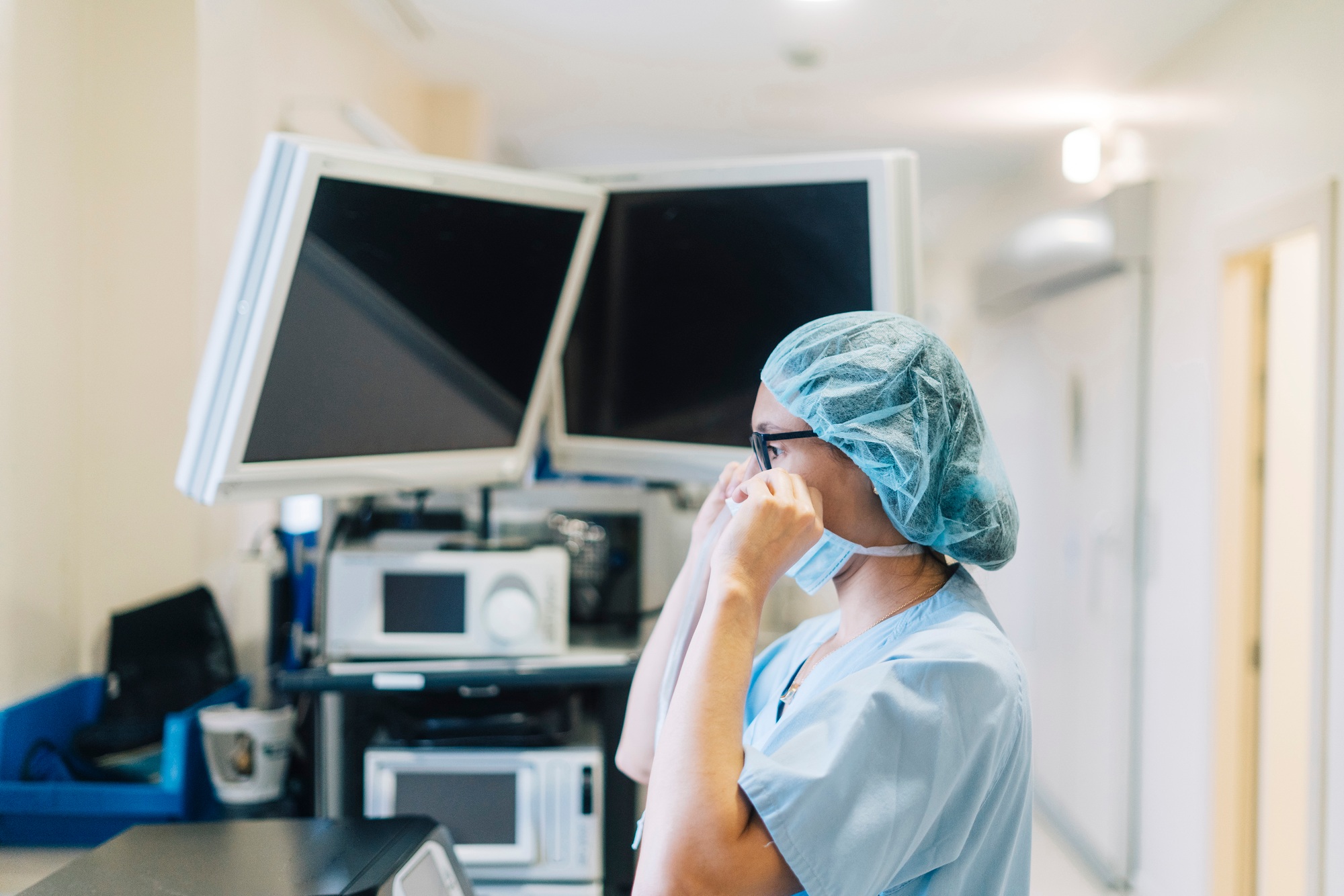 Female doctor tying surgical mask, preparing for surgery