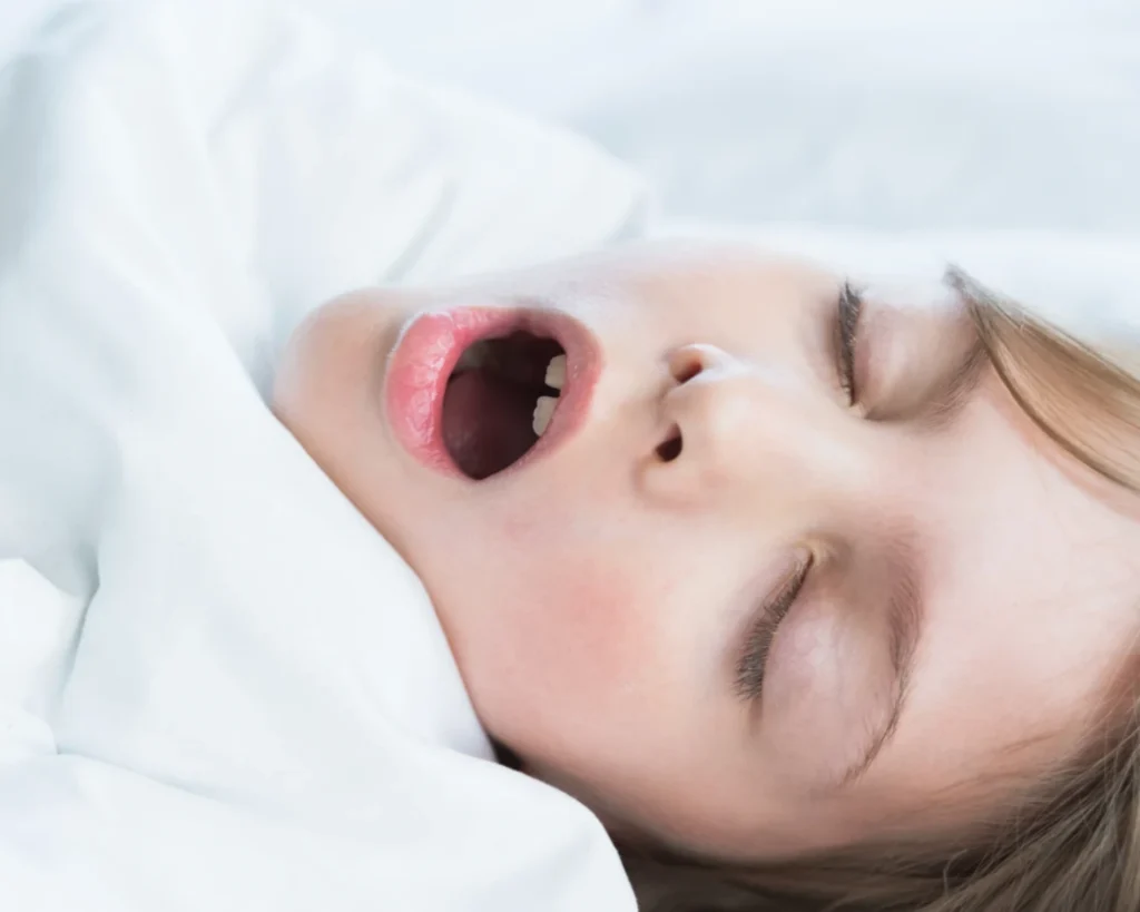 child sleeping soundly under white  blanket